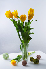 bouquet of tulips in a vase on the table, light background, postcard, spring