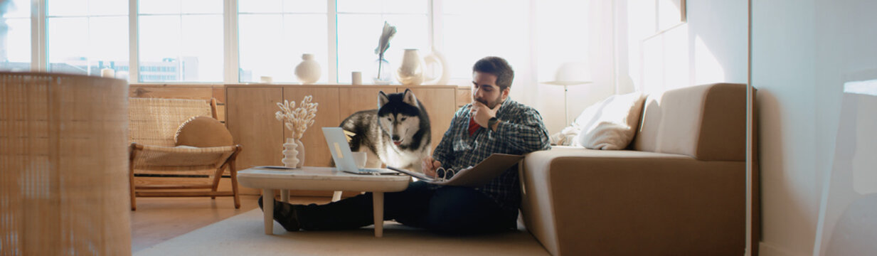 Middle Eastern male working from home, having a video call, dog sits near him. Stay home, quarantine remote work