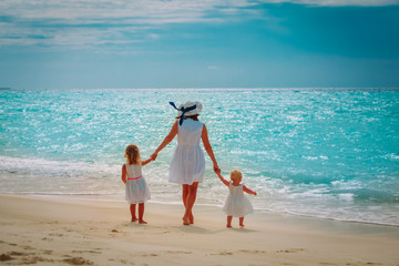 Mother with little daughters walk on sand beach