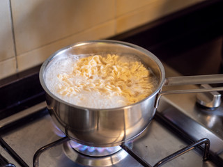 Instant noodles cooking over a stove on an open fire
