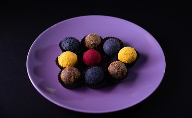 Colored round candies on a plate on a dark background. Flatlay