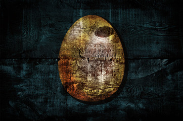 Golden easter egg shape on old wooden boards. Dark grunge background with wooden texture. Happy easter creative greeting card design. Golden wood texture. Background for poster, banner