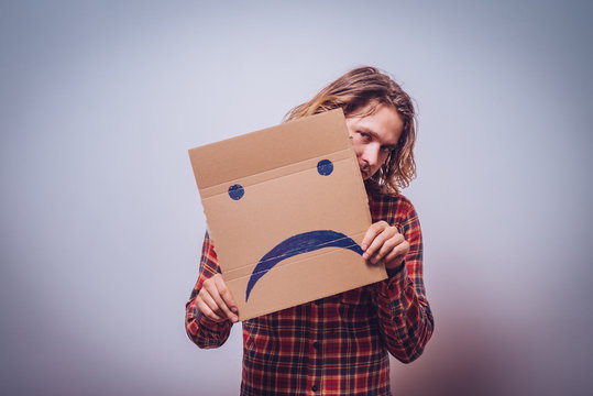 man  holding a picture with a unhappy smiley