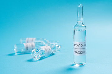 Coronavirus vaccine. Glass ampoules with a medicine for COVID-19 on a blue background. Copyspace. Close-up. Search and application of a new injection