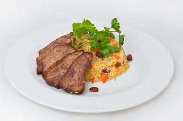 Thin slices of young veal and a slice of sweet pilaf with raisins and a sprig of parsley