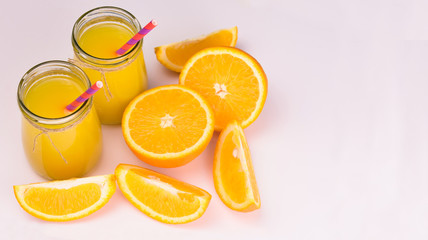  Orange juice in glass jars and fresh oranges on a white background. Copy space.