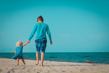 father and little daughter walk on beach