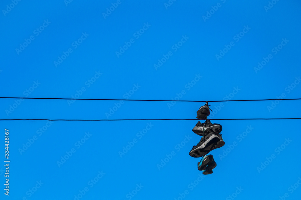 Wall mural Sneakers hanging on wires against a blue sky