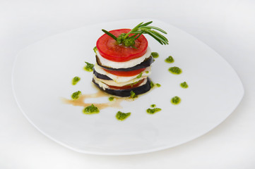 Fried eggplant in circles alternating with mozzarella, tomatoes and a sprig of rosemary