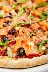 Sliced pizza with salmon, calamata olives and sun dried tomatoes