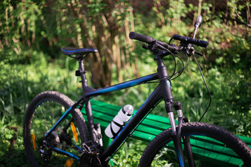 Fototapeta na wymiar Sports black bike in the park near the benches with blurry background