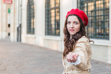 Obraz premium Beautiful young woman at city street. Happy tourist girl walking outdoors. Spring portrait of pretty brunette female posing in old town. Follow me to city