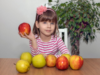 Fototapeta premium Apples lie on the table, the girl holds an apple in her hand