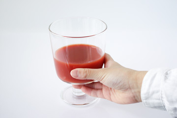 トマトジュースを持つ子どもの手