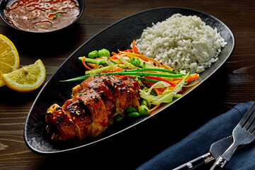 Traditional Japanese teriyaki chicken with salad made of cucumber, ginger, carrot, pepper and cabbage, rice, sesame and edamame.