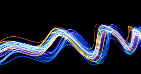 Blue and gold light painting photography, long exposure photo of metallic gold and electric blue streaks of vibrant color against a black background