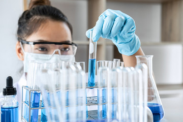 Biochemistry laboratory research, Chemist is analyzing sample in laboratory with equipment and science experiments glassware containing chemical liquid