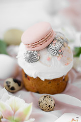 Obraz na płótnie Canvas Easter cake kulich. selective focus Traditional easter sweet bread decorated with meringues and macaroons on a plate on a background of a vase with white tulips. Copy space