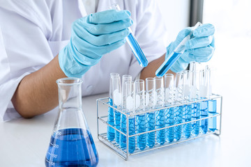 Biochemistry laboratory research, Scientist or medical in lab coat holding test tube with using reagent with drop of color liquid over glass equipment working at the laboratory