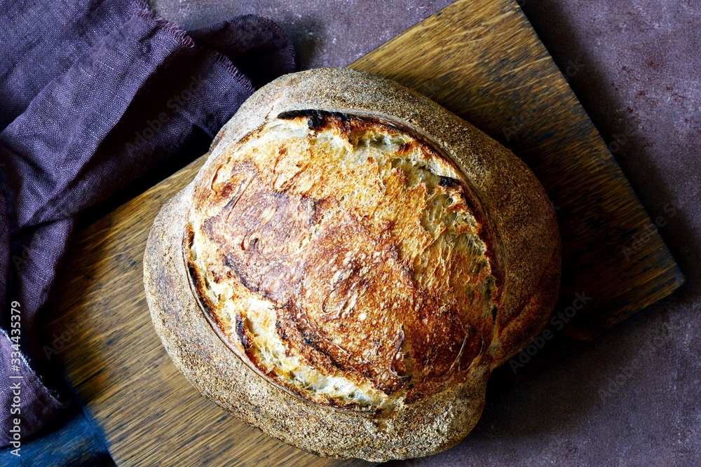 Wall mural homemade freshly baked country bread made from wheat and whole grain flour on a gray-blue background