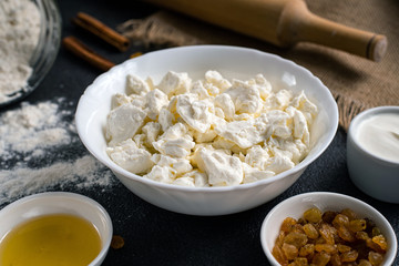Cottage cheese with sour cream and raisins on a dark background. Farm products, close-up.