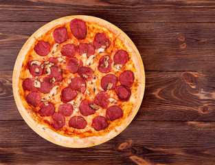 Salami pizza with mushrooms on bamboo bottom, on wooden table top view, space for text