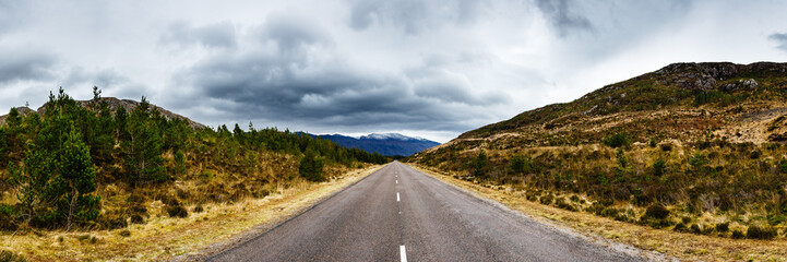 Fototapeta na wymiar Road under the cloudy sky between two hills, somwhere in Scotland