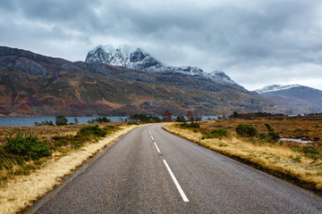 A road in a beautiful landscape beneath a snowy mountain in Scotland