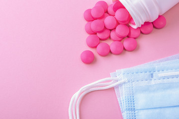 Medical mask surgical protective virus, flu, disease and pills. Isolated on a pink background.