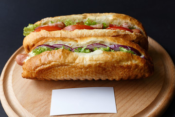Two hot dogs lying on the wooden plate. Mock up.