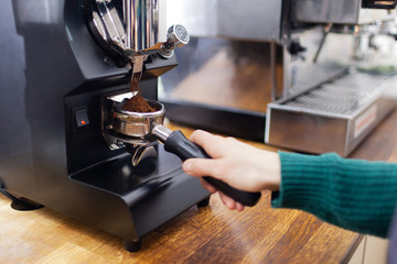 Girl barista is preparing coffee in coffe machine inside the cafeteria
