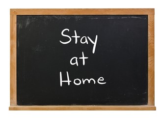 Stay at home written in white chalk on a black chalkboard isolated on white