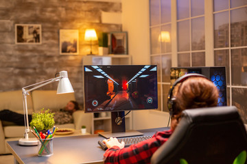 Back view of female gamer playing on powerful computer PC late at night in the living room © DC Studio
