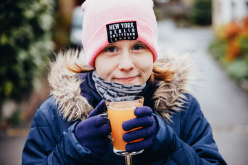 Young girl drinking popular hot non-alcoholic beverage, called Punsh. Favourite children hot drink on Christmas markets in Switzerland and in german-speaking countries.