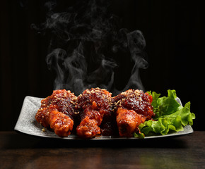 Hot and spicy bbq chicken legs with with green salad leaf and steam smoke