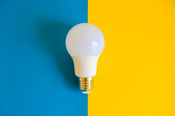 LED light bulb on blue and yellow background. Top view. Copy, empty space for text