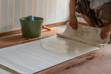 Craftsman is applying glue for the wallpaper. Wallpaper installation process