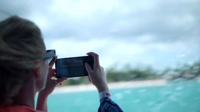 Girl Taking Picture On Cellphone.Girl Relaxing And Enjoying On Sightseeing Boat Trip.Female Hands Holding Smartphone And Shooting Pictures Seashore.Blonde Fluttering Hair On Wind In Excursion Vessel.