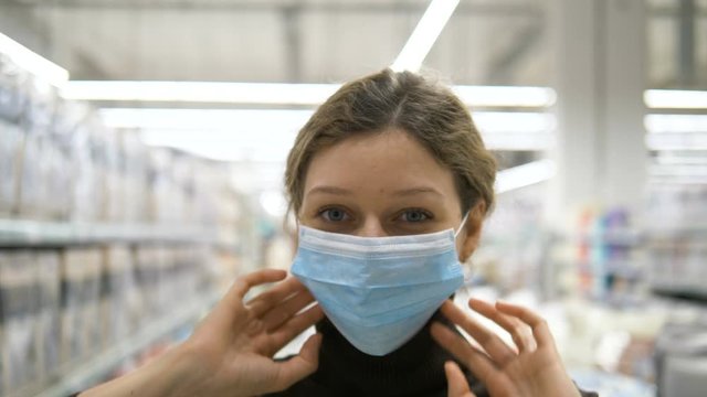 girl puts on a medical protective mask and gives thumbs up in supermarket