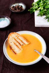 Healthy Vegetable Cream Soup in a bowl with toast grill on linen tablecloth. Vertical composition. Selective focus