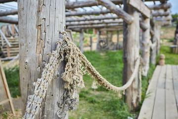 An old fishing net, spread out on the wooden pillars of the building.