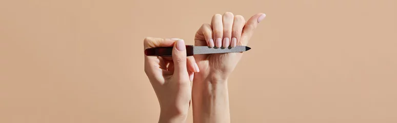  Cropped view of woman filing nails isolated on beige, panoramic shot © LIGHTFIELD STUDIOS