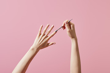 Cropped view of woman doing manicure with cuticle pusher isolated on pink - obrazy, fototapety, plakaty
