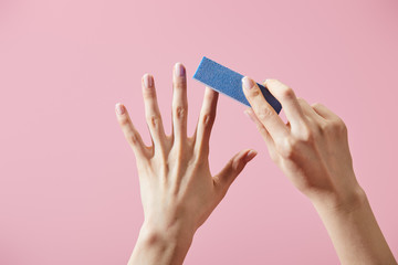 Partial view of woman doing manicure with nail buffer isolated on pink - obrazy, fototapety, plakaty