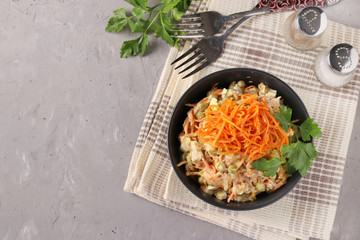 Salad with Korean carrots, meat and canned peas in a dark bowl on a gray background, Copy space