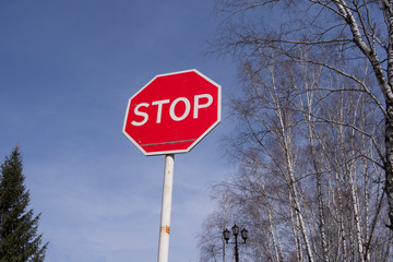 Stop sign against the sky and trees. Danger warning.