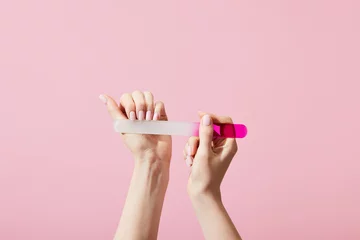 Foto op Plexiglas Bijgesneden beeld van vrouw die manicure doet met nagelvijl geïsoleerd op roze © LIGHTFIELD STUDIOS