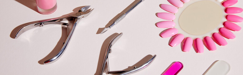 High angle view of samples of nail polish with manicure instruments on white, panoramic shot