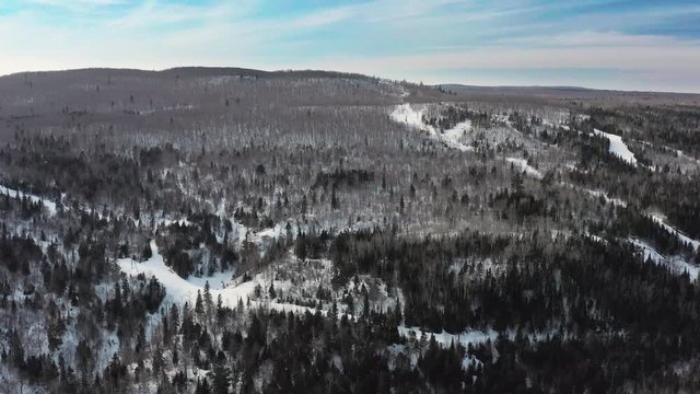 aerial drone view flying over vast snowy forest with rocks and cliffs and hills in winter wilderness in northern minnesota