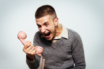 Close up image of a man screaming on the telephone during the conversation.